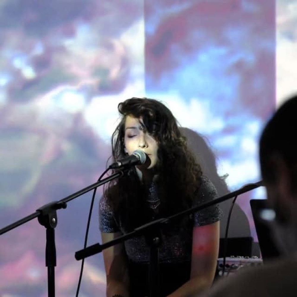 NINA singing live, projected light behind her